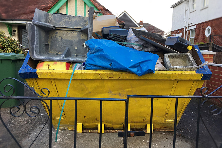 Closeup full industrial skip with variety of material inside the heavy bin.