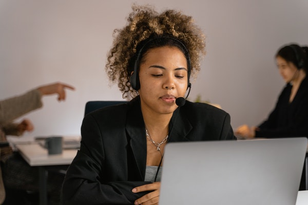 A customer support agent talking on a headset in front of a computer screen