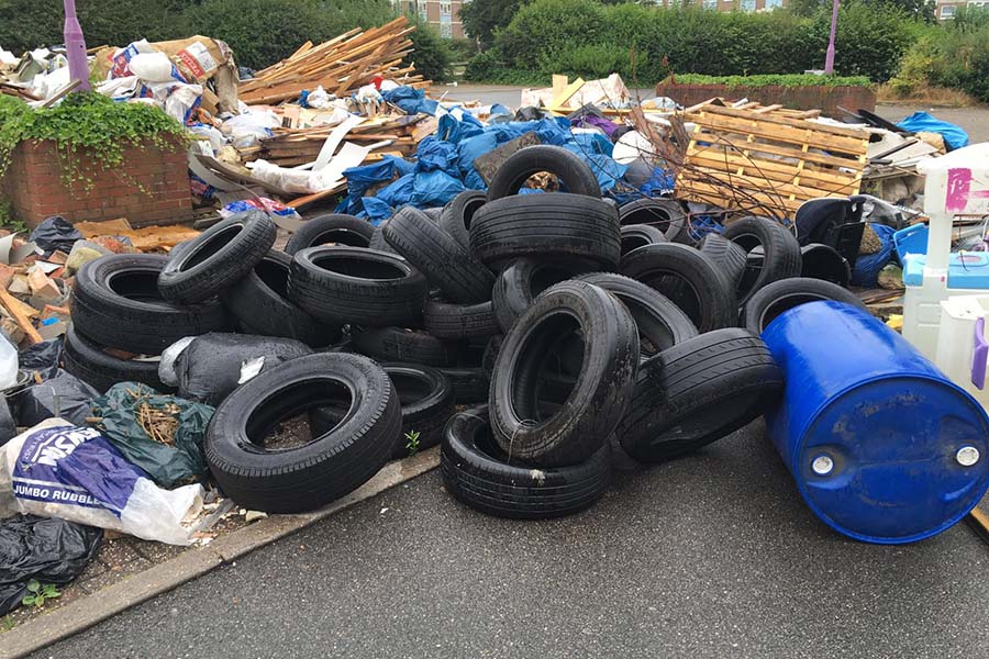 A pile of tyres that have been dumped next to a roadway