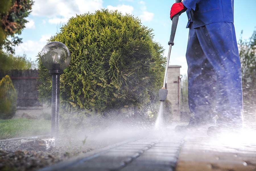 A person pressure washing a driveway