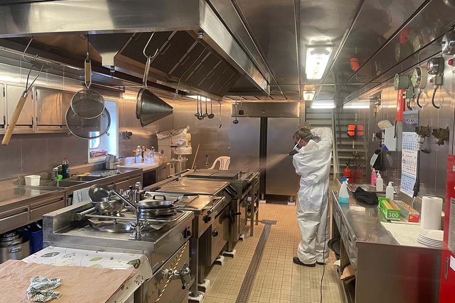 A technician using a fogging machine to disinfect a contaminated area