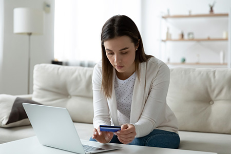 Focused young woman entering banking credit card information in computer application