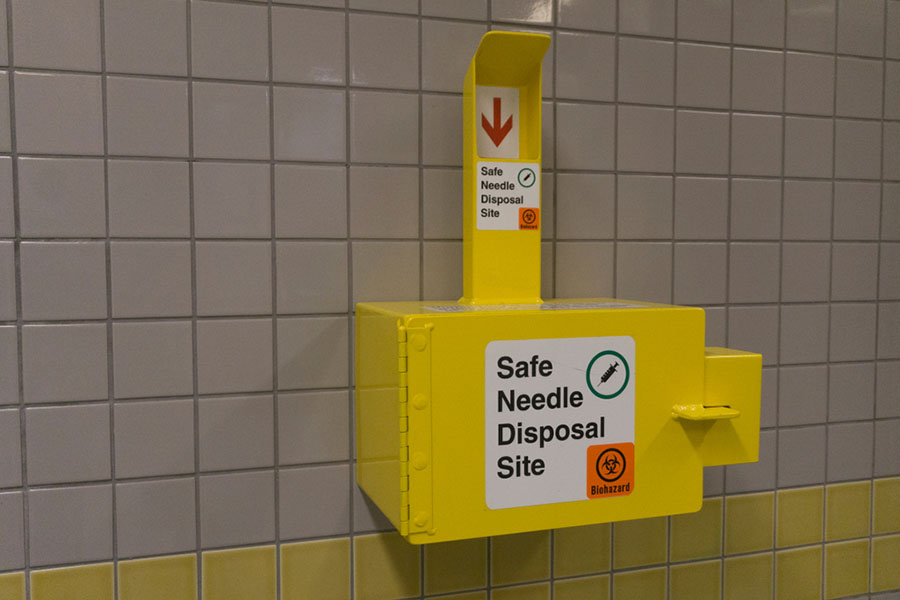 Safe medical needle disposal container on a toilet wall