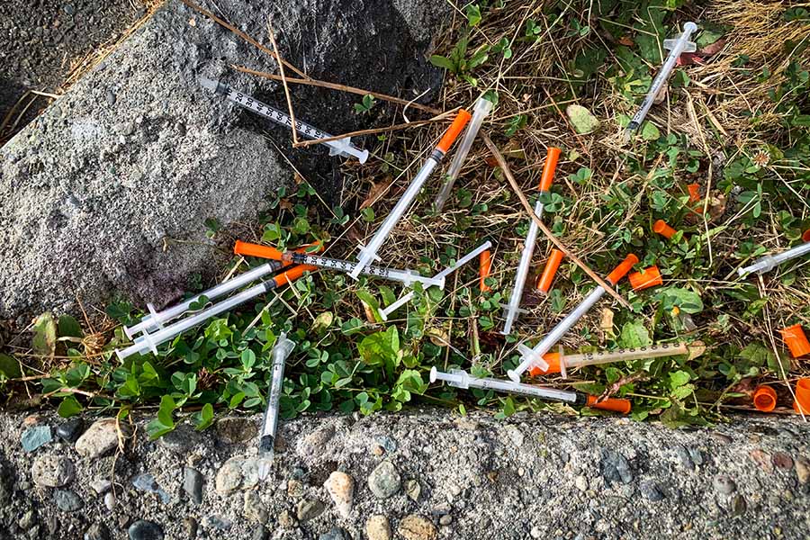 A large number of used needles laying in a grassy area