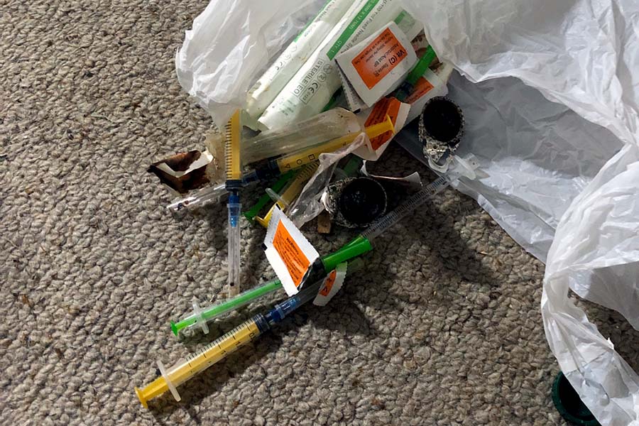 Used hypodermic needles laying amongst a pile of rubbish during a needle sweep